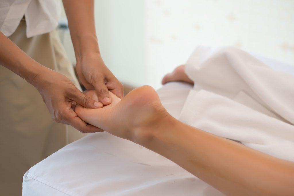 close up of massage therapist massaging female leg at spa salon.